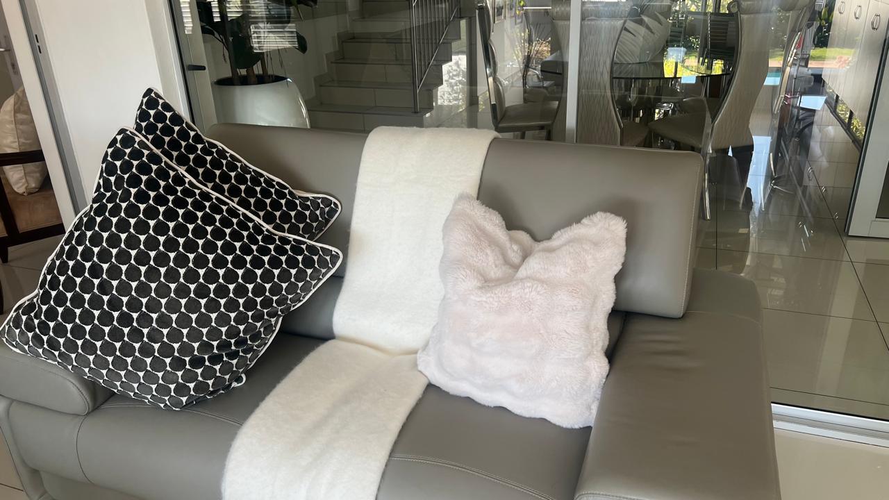 Patterned scatter cushions and a faux-fur throw styled on a grey leather sofa
