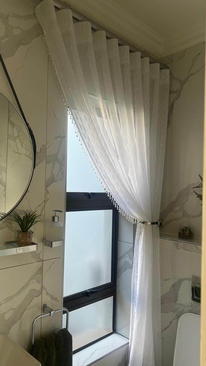 Sheer curtain tied back in a marble bathroom